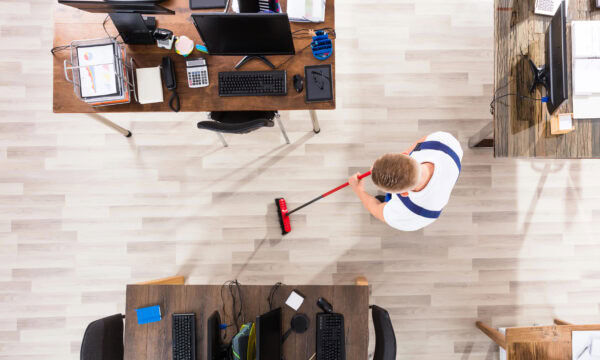 Elevated View Of Male Janitor Cleaning Floor With Broom At Workplace